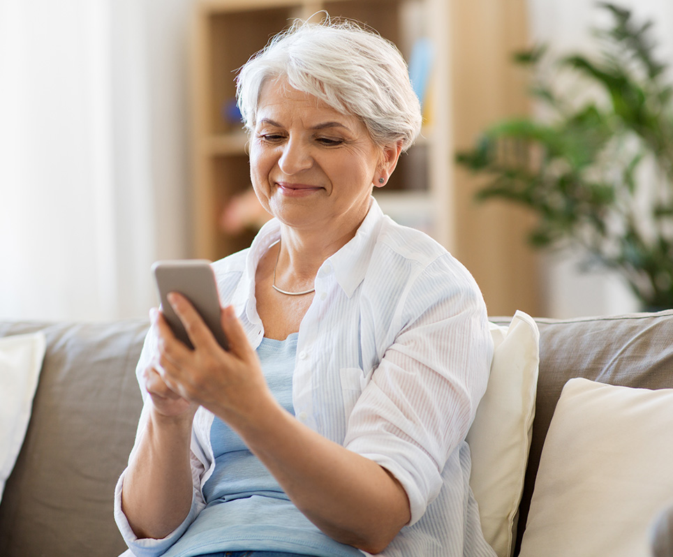 Senior woman at home looking at smartphone